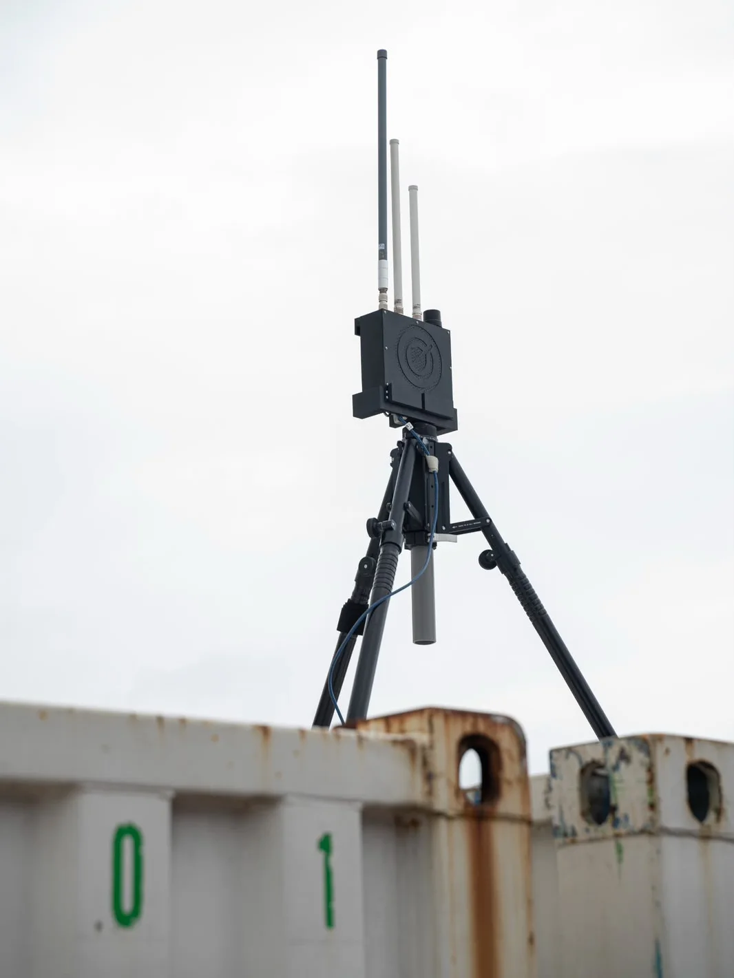 Een AEROTECT DRID op statief tegen de lucht, met de drie antennes en het AEROTECT-logo op de behuizing